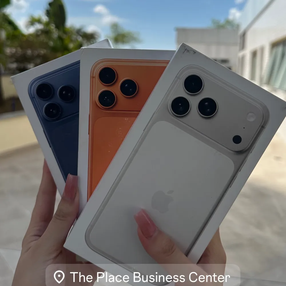 Três iPhones em cores diferentes nas mãos de uma cliente em frente ao The Place
